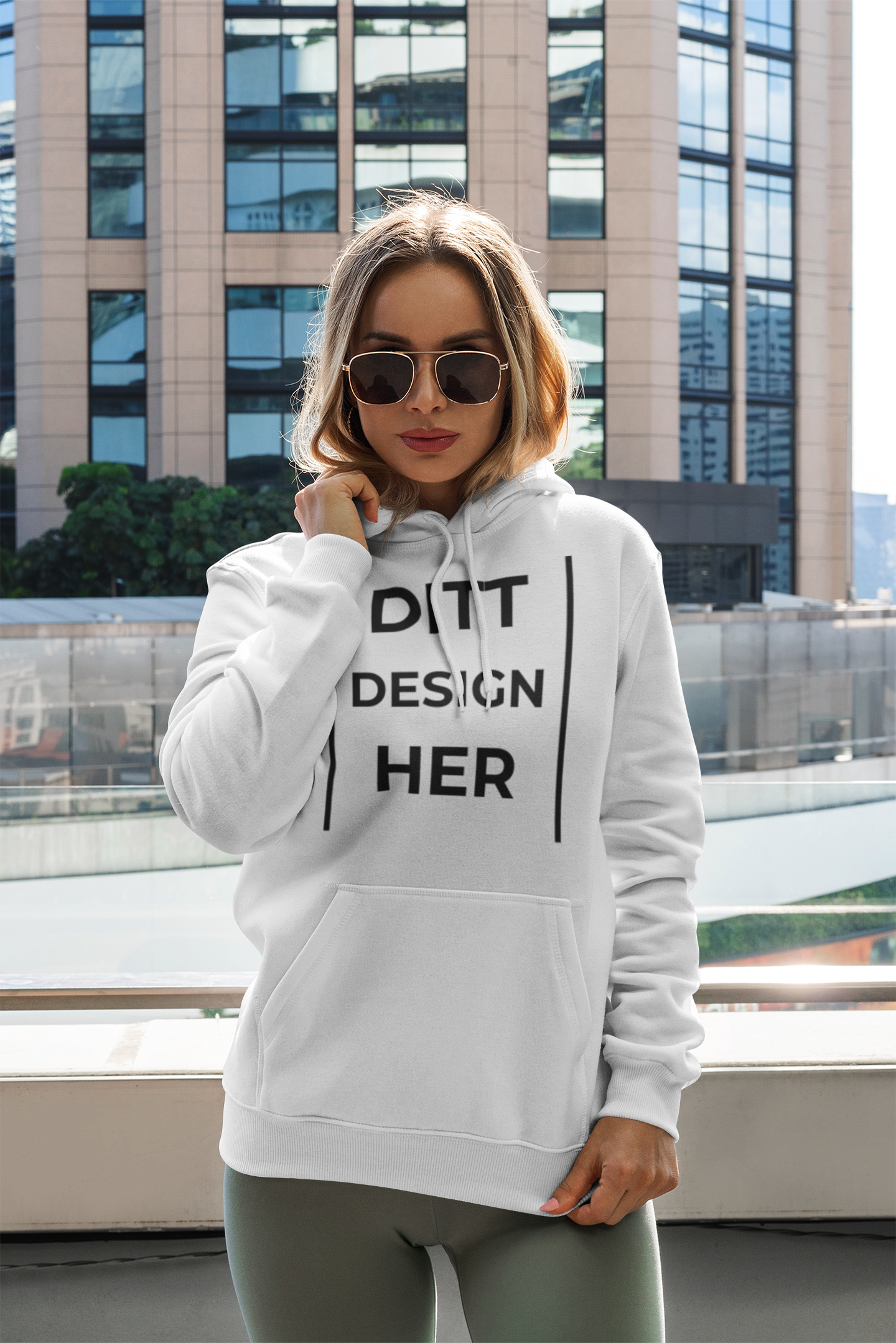 mockup-of-a-woman-with-a-pullover-hoodie-posing-by-a-tall-building-3549-el1 Modell med eget merch